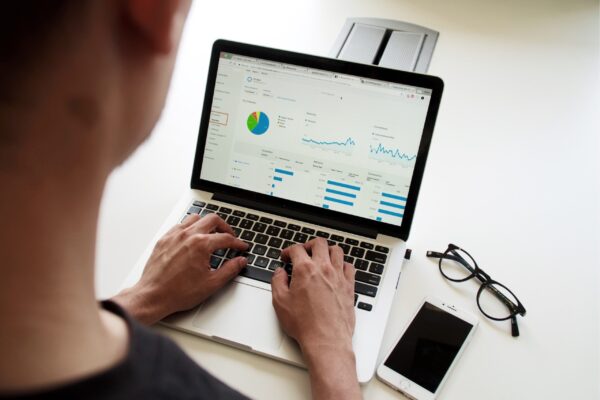 Person analyzing digital marketing performance metrics on a laptop, with graphs and data dashboards on the screen.