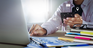 man using laptop with a smartphone in his hand