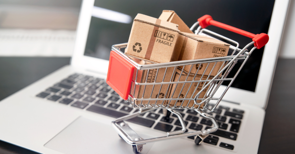 A miniature shopping cart on top of a laptop.