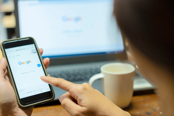 A woman using her phone and laptop to go to Google