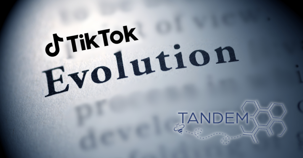 A page from a dictionary that is turned to the word Evolution, with all words surrounding it blurred. The TikTok word logo is on the top left corner. The Tandem.Buzz logo is in the bottom right corner. This indicates the blog discusses TikTok's Evolution Into a Discovery Hub and Consumer Sentiment Tool.