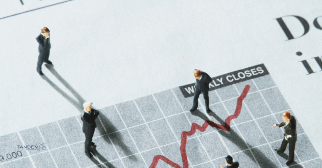 Miniature business figures standing on a financial chart labeled “Weekly Closes,” observing a rising red trend line; Tandem Digital Marketing logo in the corner.