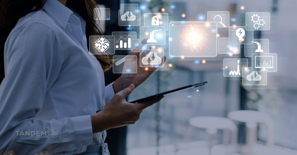 Business professional using a tablet surrounded by digital interface icons representing cloud computing, data analytics, automation, and AI; Tandem Digital Marketing logo visible.