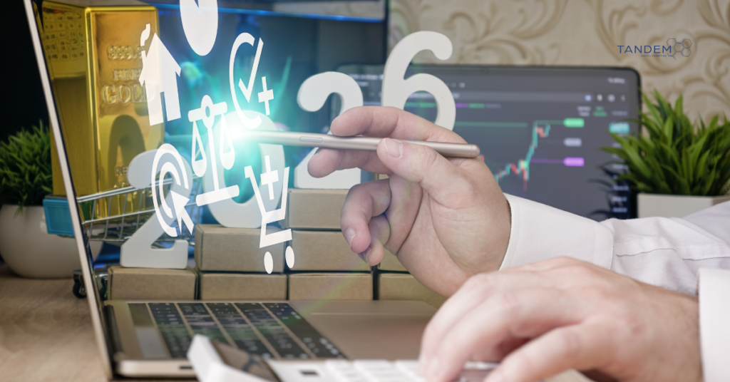 A professional strategist using a stylus to analyze 2026 digital marketing growth trends on a laptop, featuring the Tandem Interactive logo, holographic data icons, and symbols of high-value ROI and financial success.