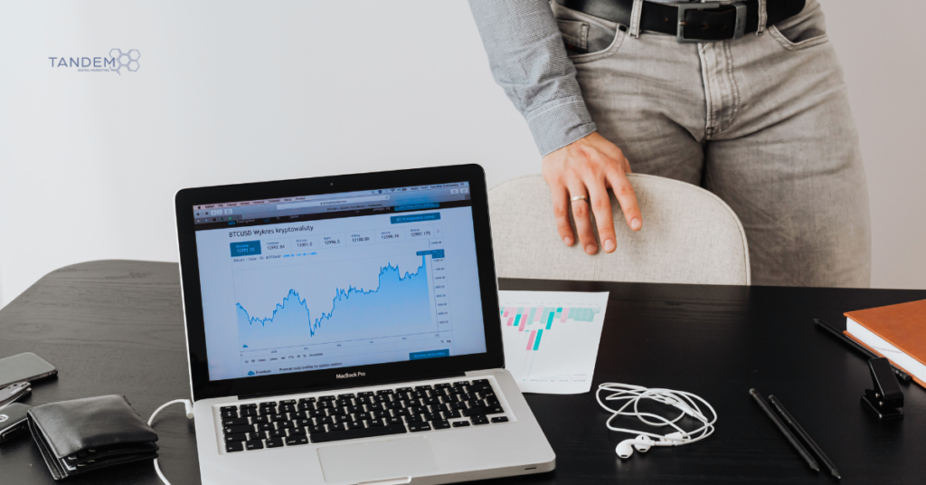 A clean, professional workspace showing a MacBook Pro displaying a market growth chart and data trends, representing Tandem Interactive’s February 2026 digital marketing updates and strategic performance reviews.