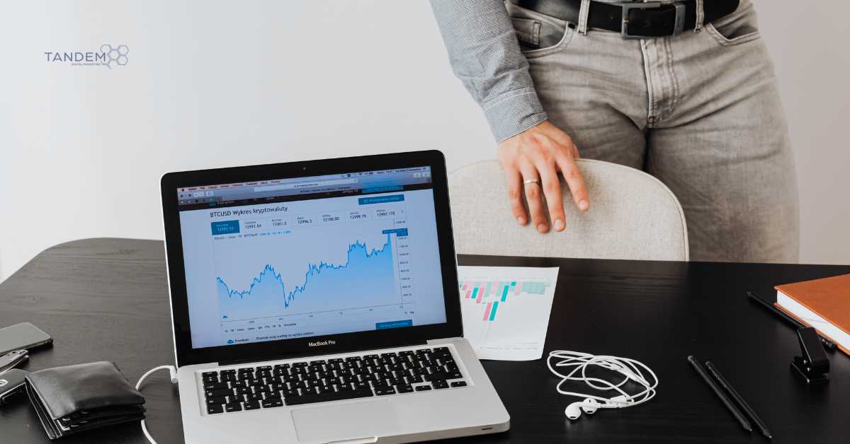 A clean, professional workspace showing a MacBook Pro displaying a market growth chart and data trends, representing Tandem Interactive’s February 2026 digital marketing updates and strategic performance reviews.