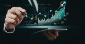 A professional digital marketer using a stylus to interact with a glowing financial growth chart on a tablet, featuring Tandem Interactive branding and icons representing e-commerce and global marketing reach.