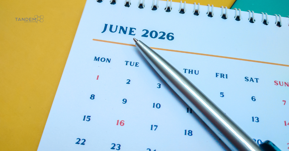 A clean, close up view of an open spiral calendar page displaying June 2026 with a silver pen resting on top, featuring Tandem Interactive branding for our midyear digital marketing updates.