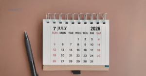 An overhead view of a desk with a pen resting next to a small spiral desktop calendar open to July 2026, displaying the Tandem Interactive logo and highlighting our monthly digital marketing updates.